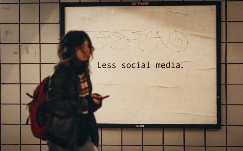 a woman standing in front of a sign that says less social media