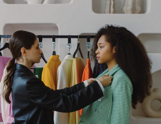 Fashion stylist adjusts outfit for model in chic boutique.