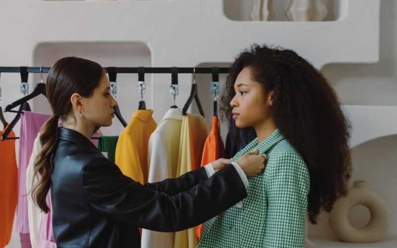 Fashion stylist adjusts outfit for model in chic boutique.