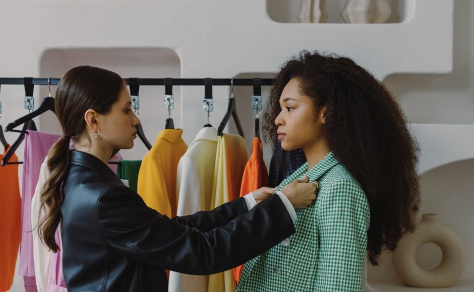 Fashion stylist adjusts outfit for model in chic boutique.