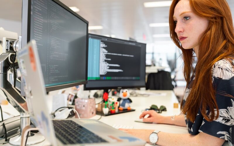 woman in green shirt sitting in front of computer